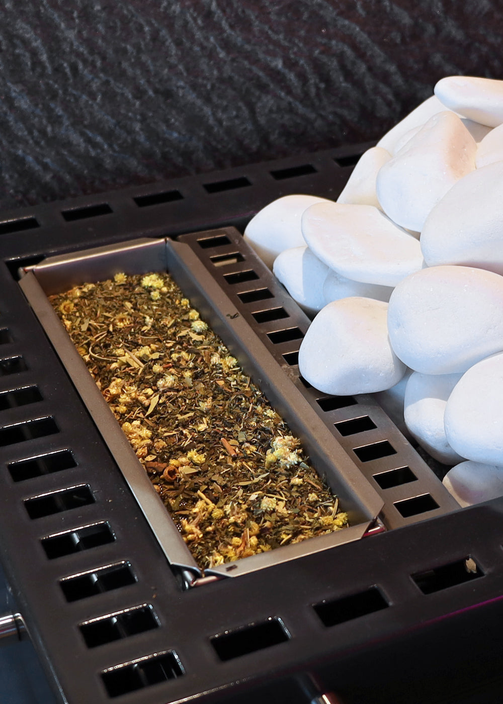 Biosauna-Verdampferofen mit Kamillenblüten auf Kräutersieb, weiße Saunasteine