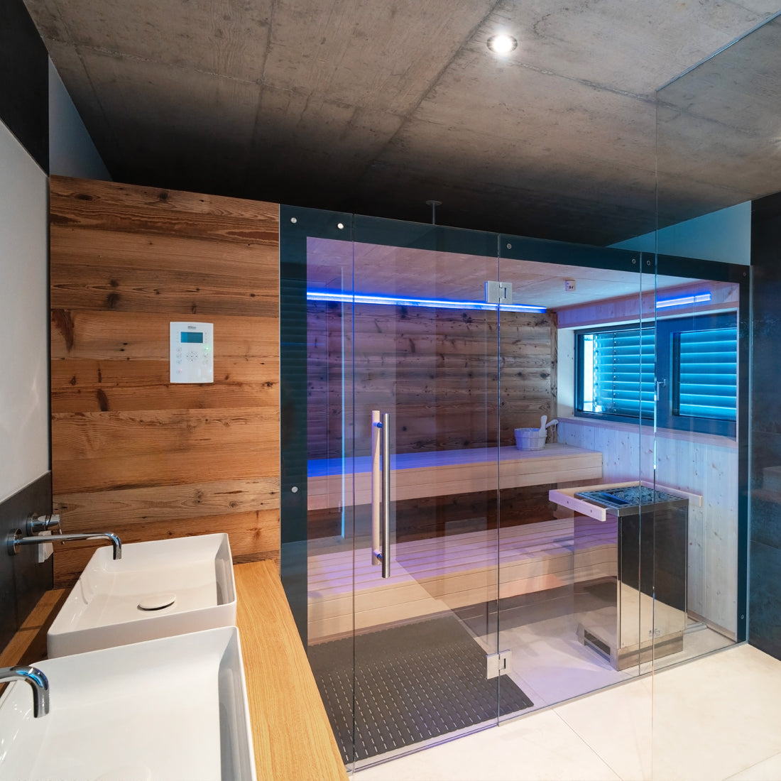 Innensauna im kubischem Stil, fügt sich optimal in das moderne, mit Beton und Steinplatten versehene Badezimmer